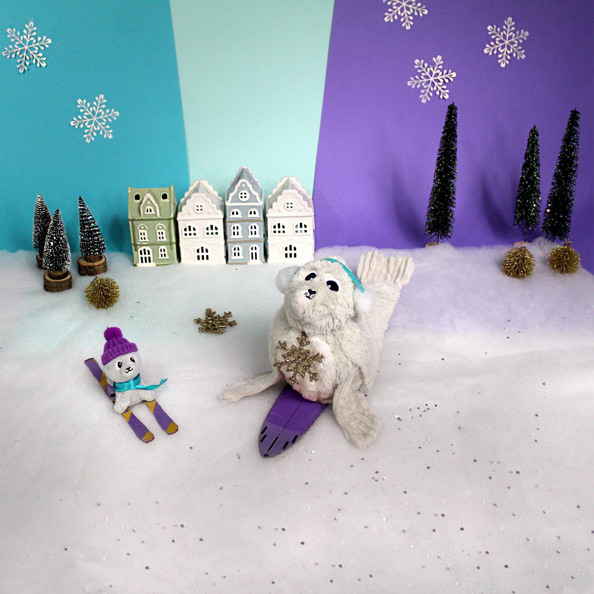 Peluche otarie Ploufou maman et son bébé gris clair - Visuel d'ambiance de la maman otarie et de son bébé en train de skier sur la banquise - Les Ptipotos